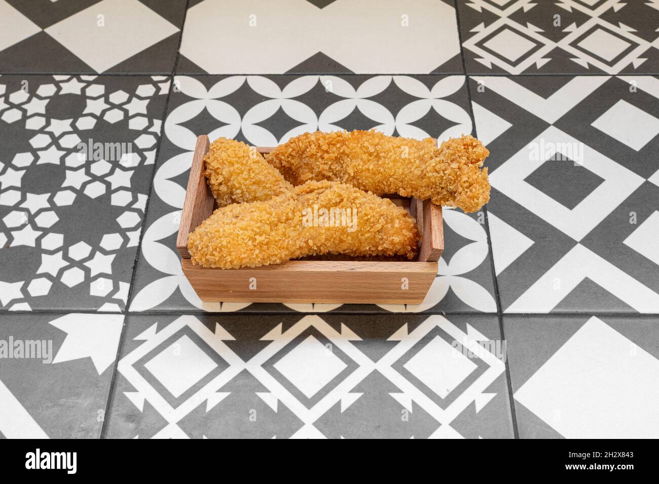 Crispy chicken breaded in panko fried in olive oil on hydraulic tiles
