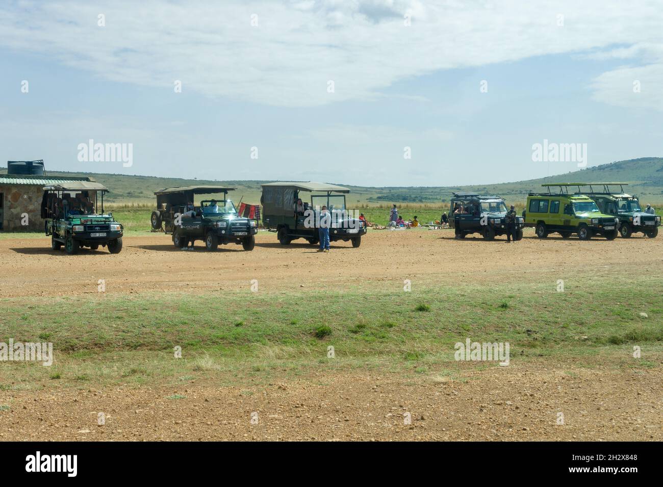 A row of 4x4 vehicles waiting for incoming tourists arriving at Keekorok airstrip, Masai Mara, Kenya Stock Photo