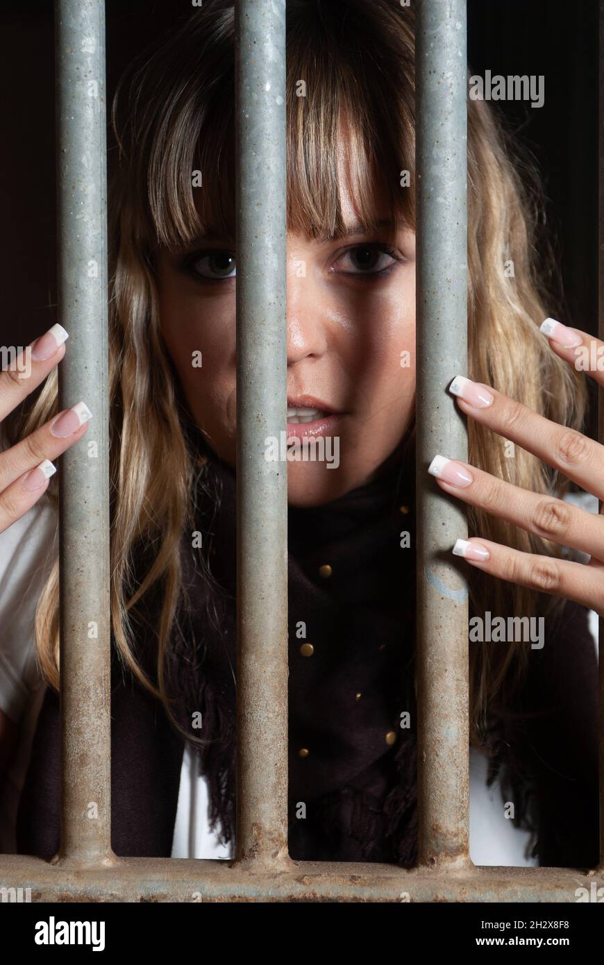 female rider locked in the stables behind bars Stock Photo Alamy