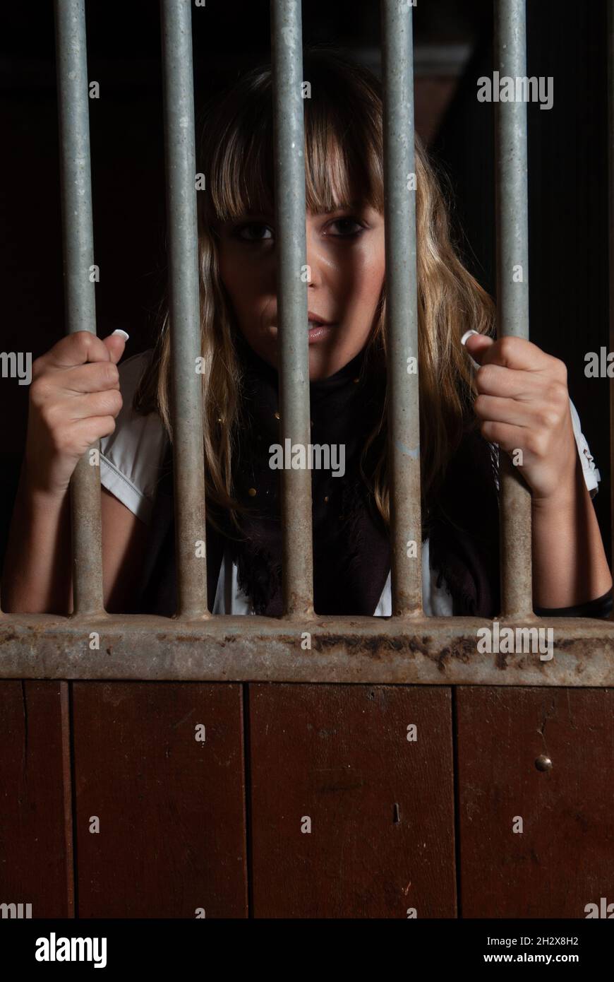 female rider locked in the stables behind bars Stock Photo Alamy