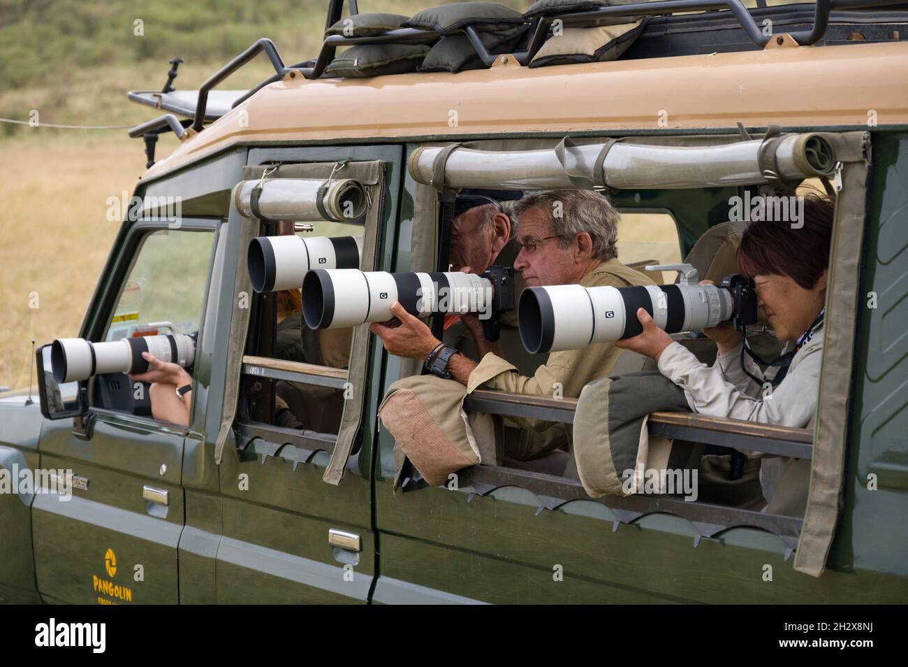 Group of tourists in a 4x4 Toyota landruiser with large SLR camera waiting, Masai Mara, Kenya Stock Photo