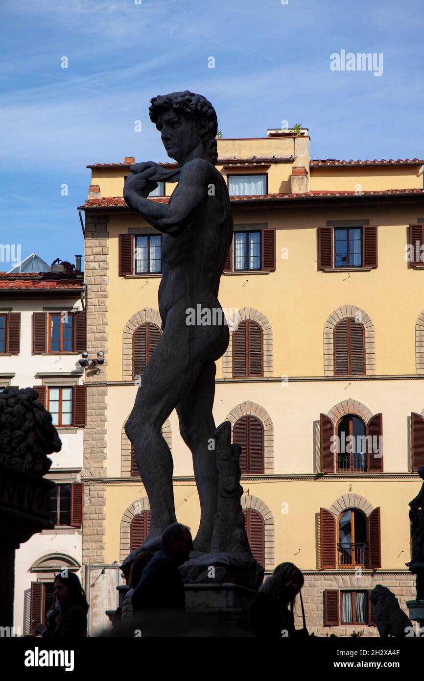 Statue of David by Michelangelo at the entrance of Palazzo Vecchio in Florence, Italy, in silhouette against a yellow italian mansion and a blue sky. Stock Photo