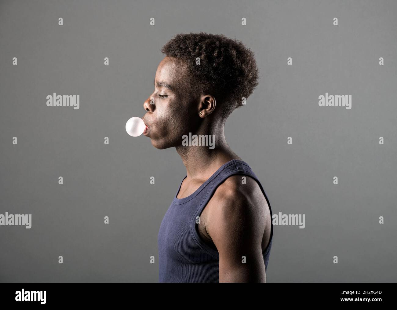 Side view of a trendy sporty young Black man in T-shirt blowing bubbles ...