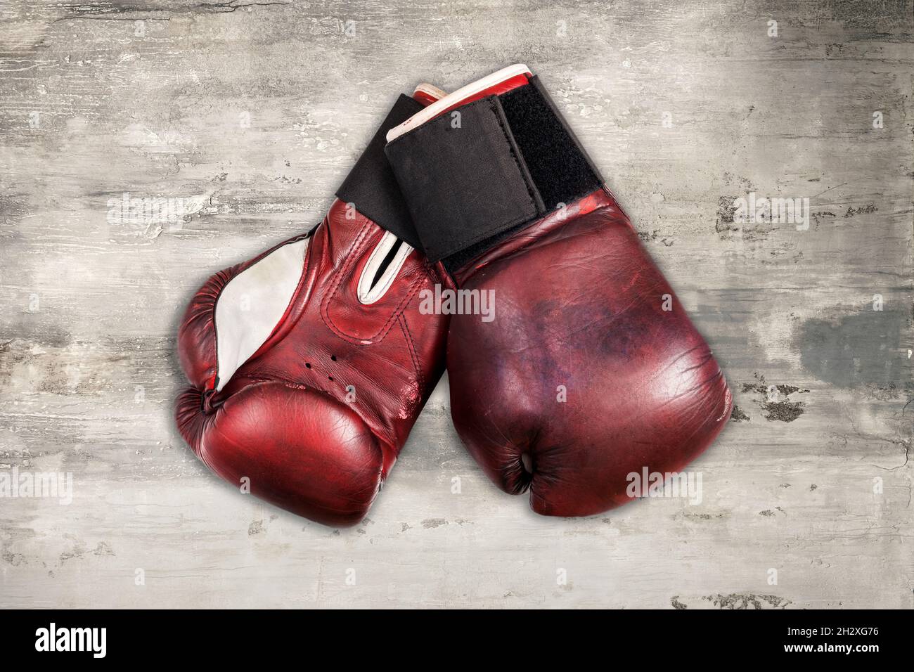 From above of pair of old red leather boxing gloves placed on shabby gray wooden background Stock Photo