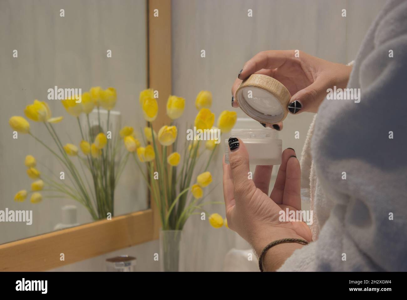 Young male hand in bathrobe holding face cream to apply after shaving. Beauty Home Spa Concept. Stock Photo