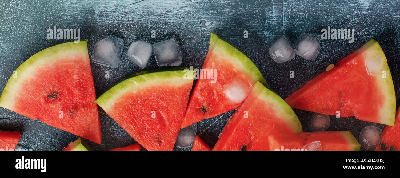 Slices of fresh watermelon with ice on a blue concrete background ...
