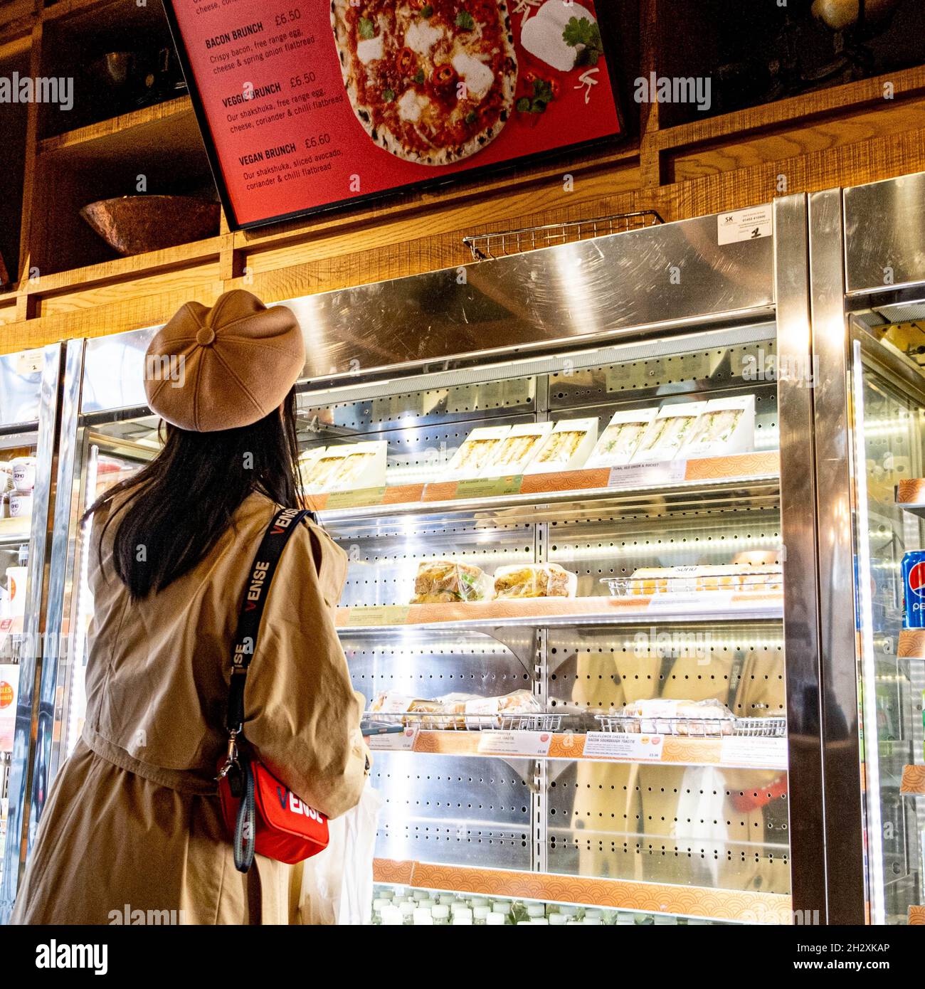 https://c8.alamy.com/comp/2H2XKAP/young-woman-alone-in-a-coffee-shop-choosing-a-sandwich-for-lunch-in-central-london-england-uk-2H2XKAP.jpg