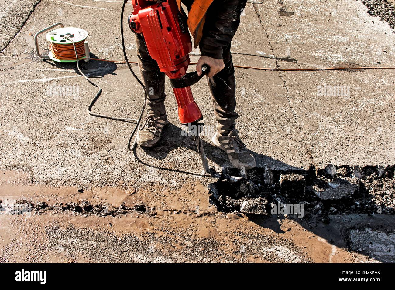Reblocking A worker repairs the road surface with a jackhammer on a summer day ...