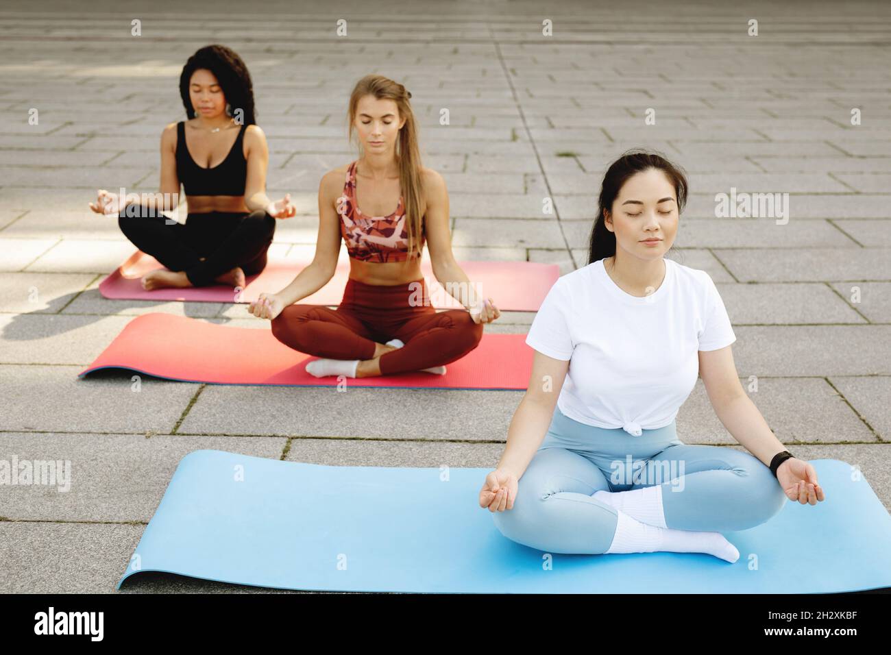 Three beautiful young women doing yoga together. Stock Photo