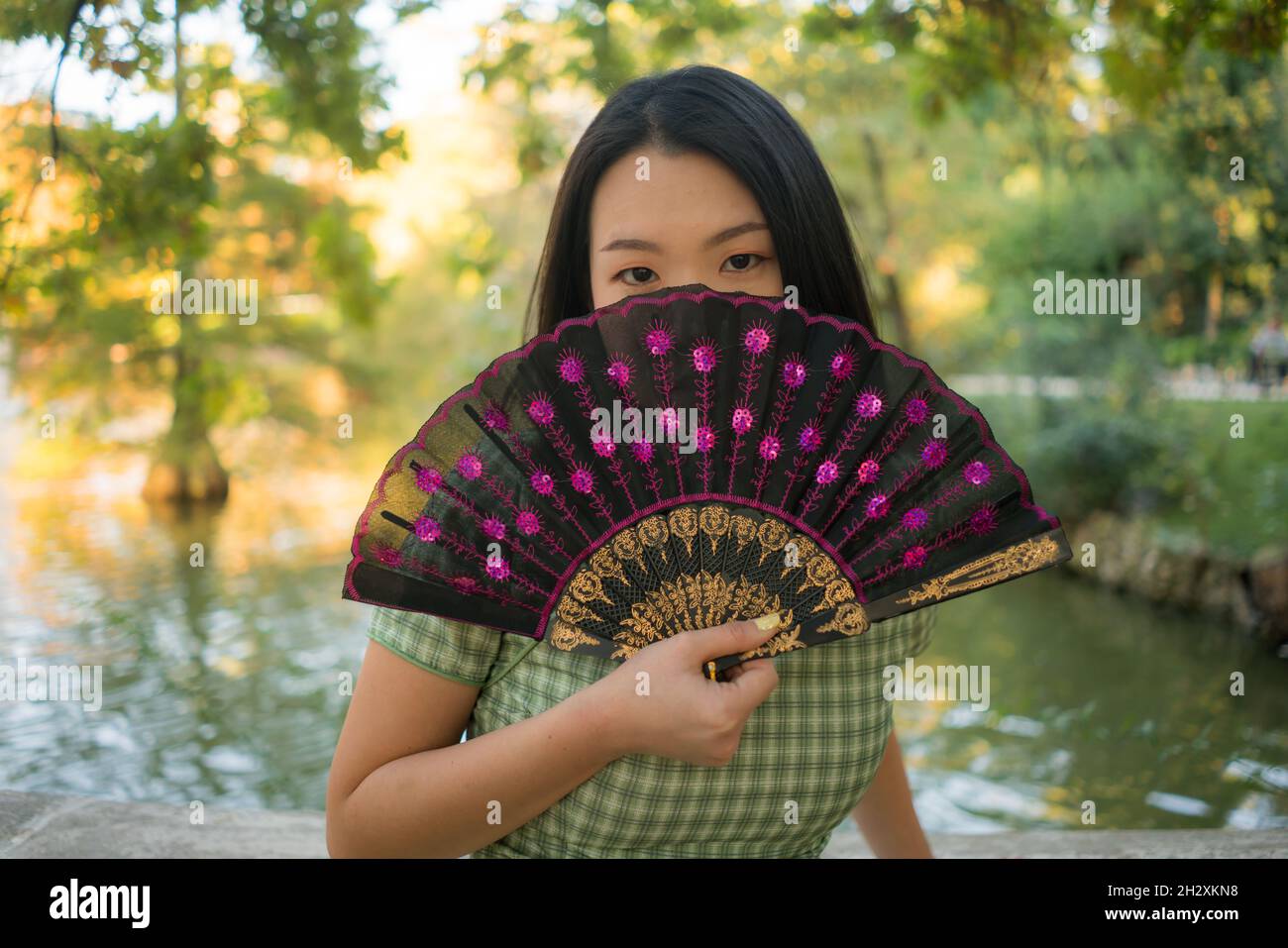 lifestyle portrait of young happy and attractive Asian Japanese woman with traditional fan relaxed taking a walk on city park enjoying Autumn nature d Stock Photo