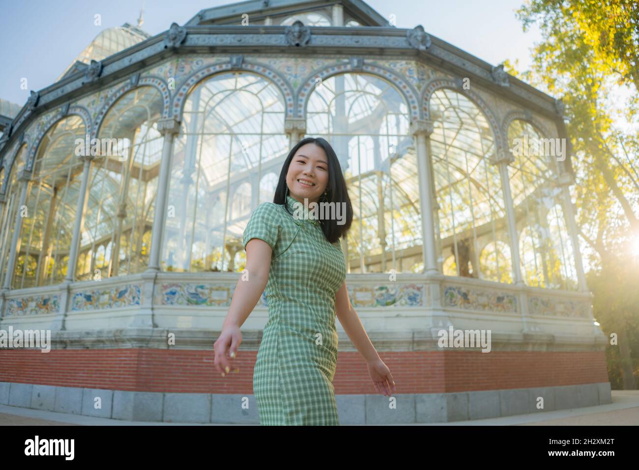 lifestyle portrait of young happy and attractive Asian Korean woman relaxed taking a walk on city park enjoying travel getaway in Spain during Autumn Stock Photo