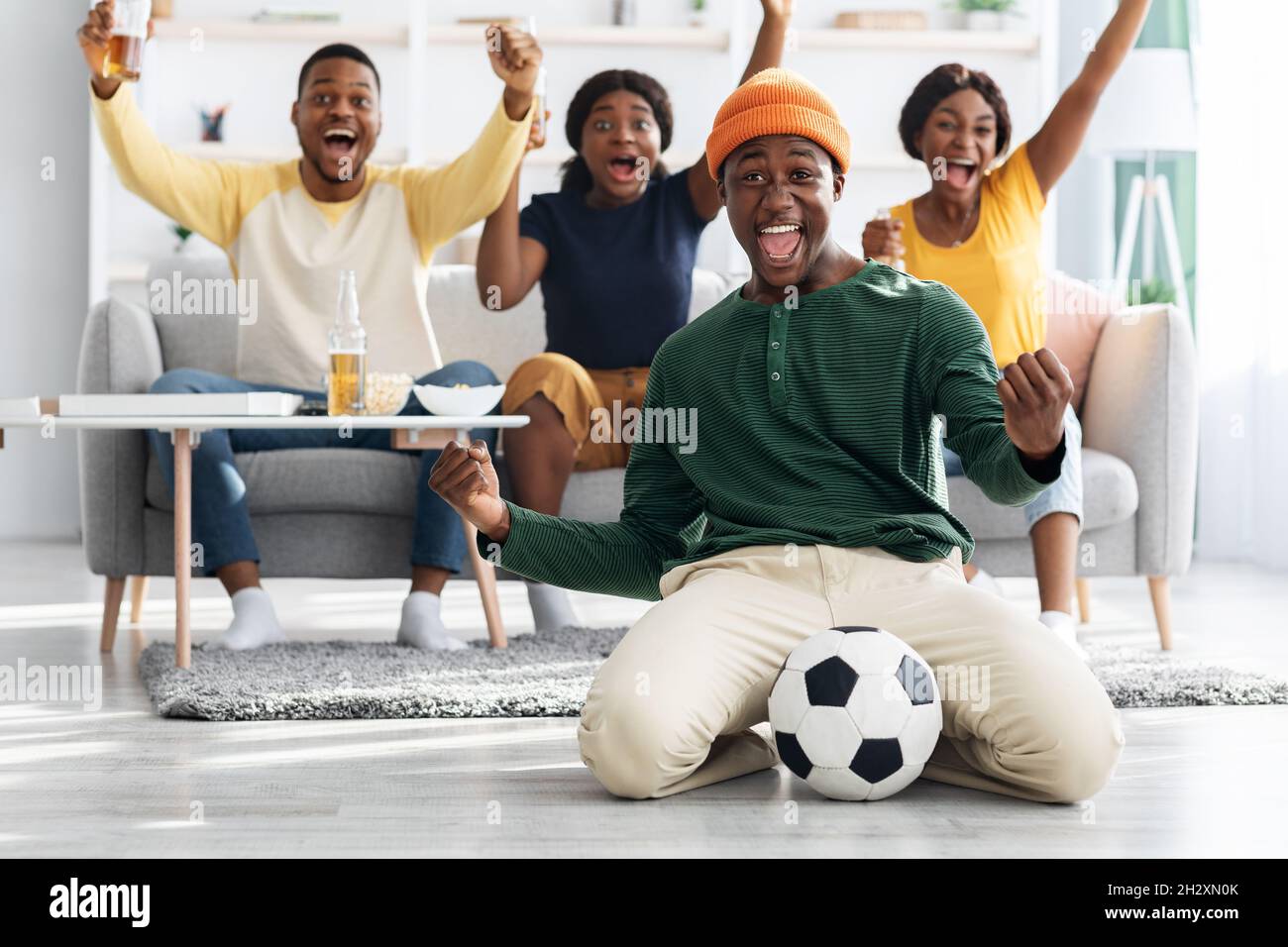 Happy african american football fans watching match on TV Stock Photo