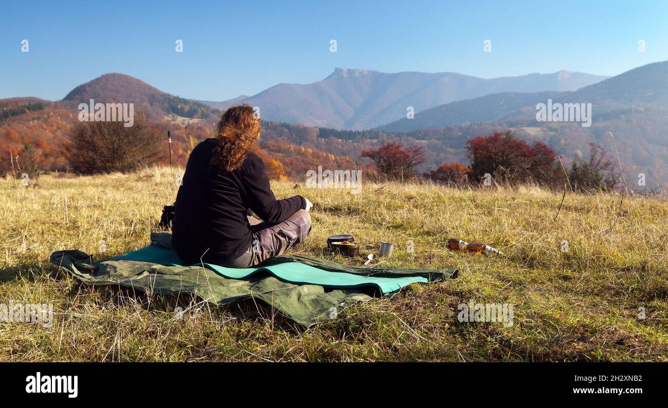 Man sitting on the meadow and Autumnal view of mount Klak, Mala Fatra from Strazovske vrchy, Slovakia Stock Photo