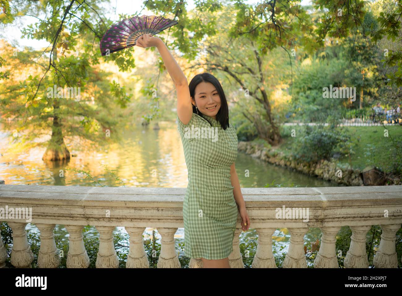 lifestyle portrait of young happy and attractive Asian Korean woman with traditional fan relaxed taking a walk on city park enjoying Autumn nature dur Stock Photo