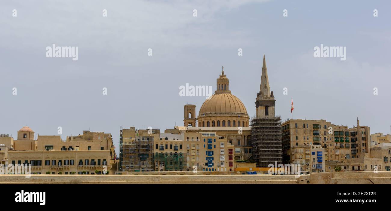 Coastal landscape of Valletta at sunny summer day, with its traditional architecture of yellow limestone. Maltese Valletta skyline with church of Our Stock Photo