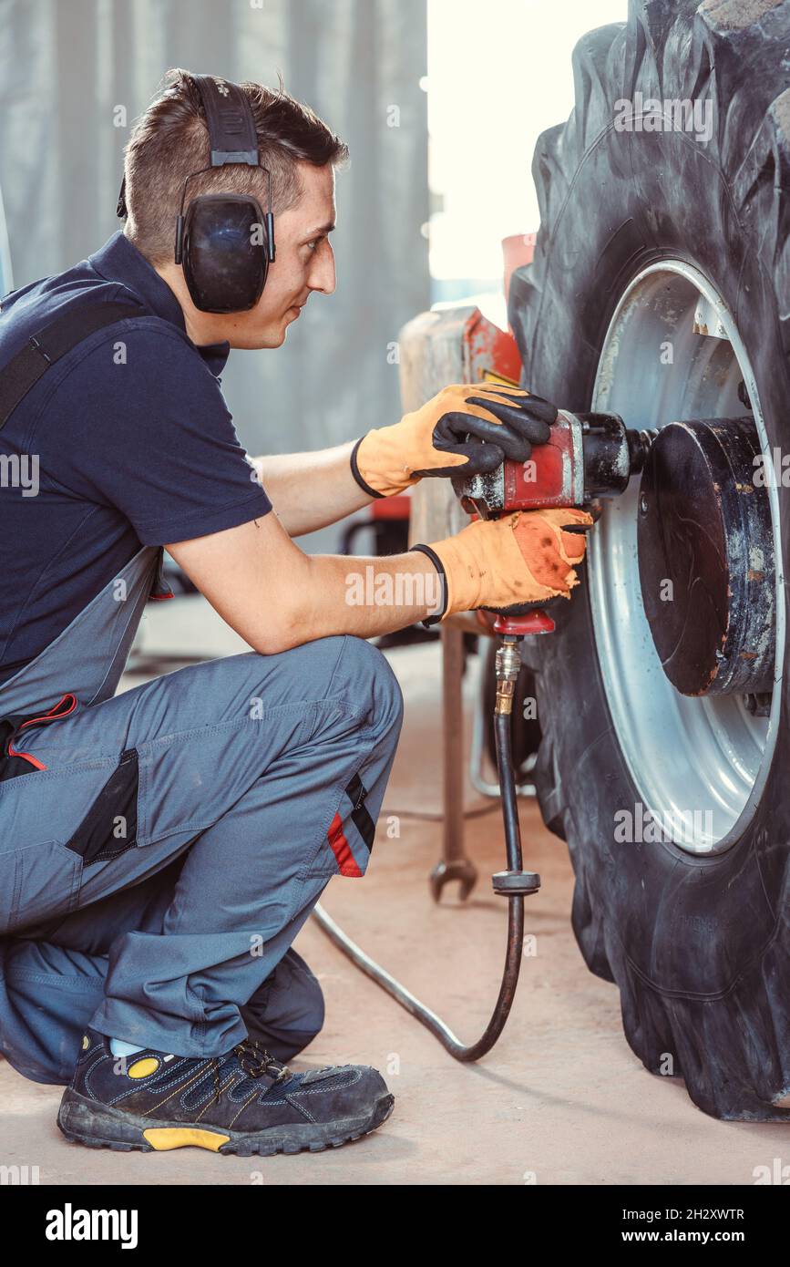 farm machine mechanic working on wheel Stock Photo Alamy