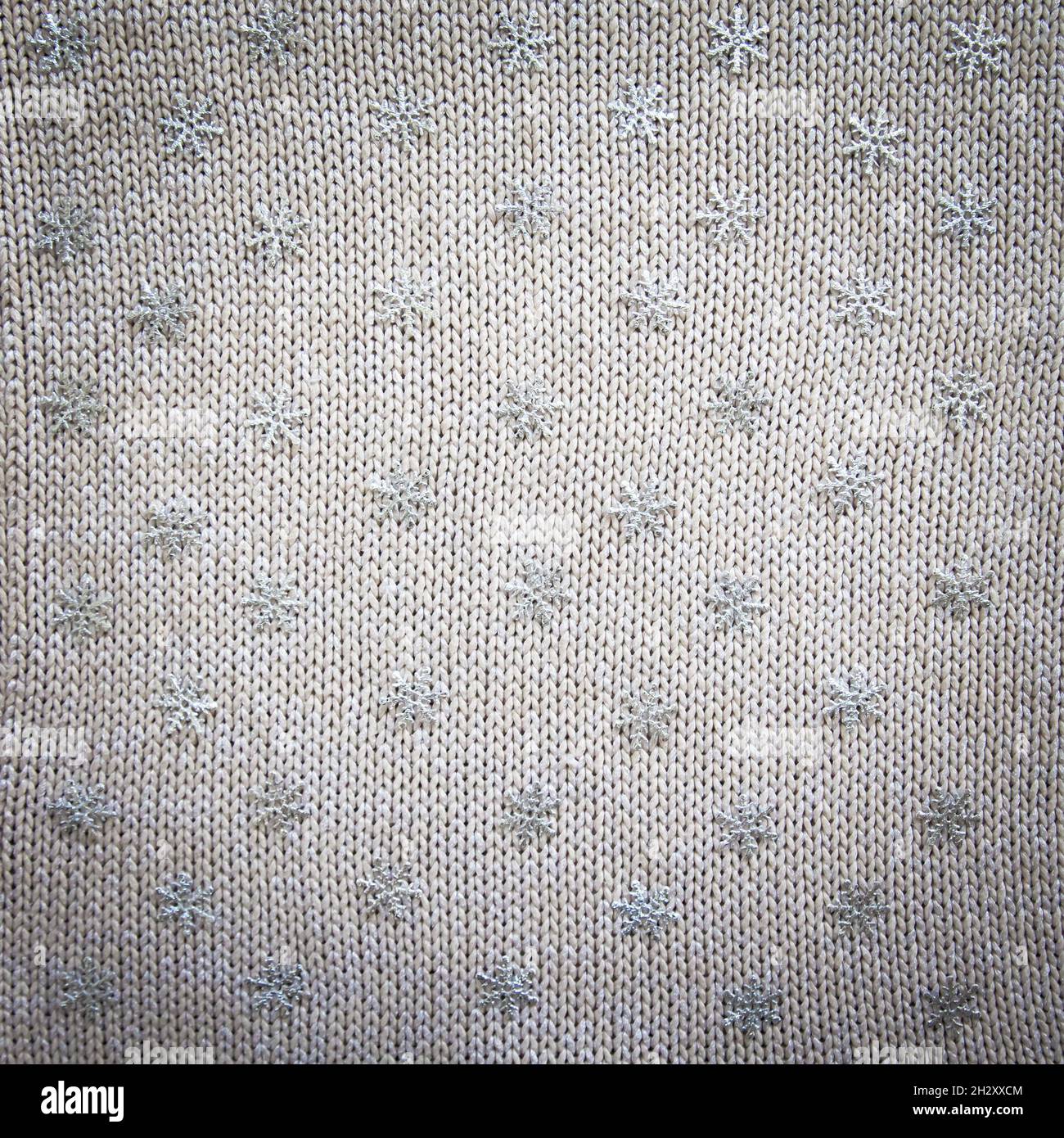 knitted background with snowflakes. Knitted fabric with sequins with snowflakes. Stock Photo