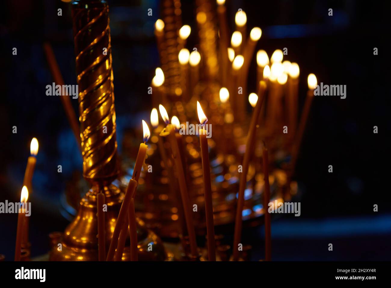 Religion and magic. Candles are burning in a dark church. In the background  is a mysterious dim light and an old chandelier Stock Photo - Alamy