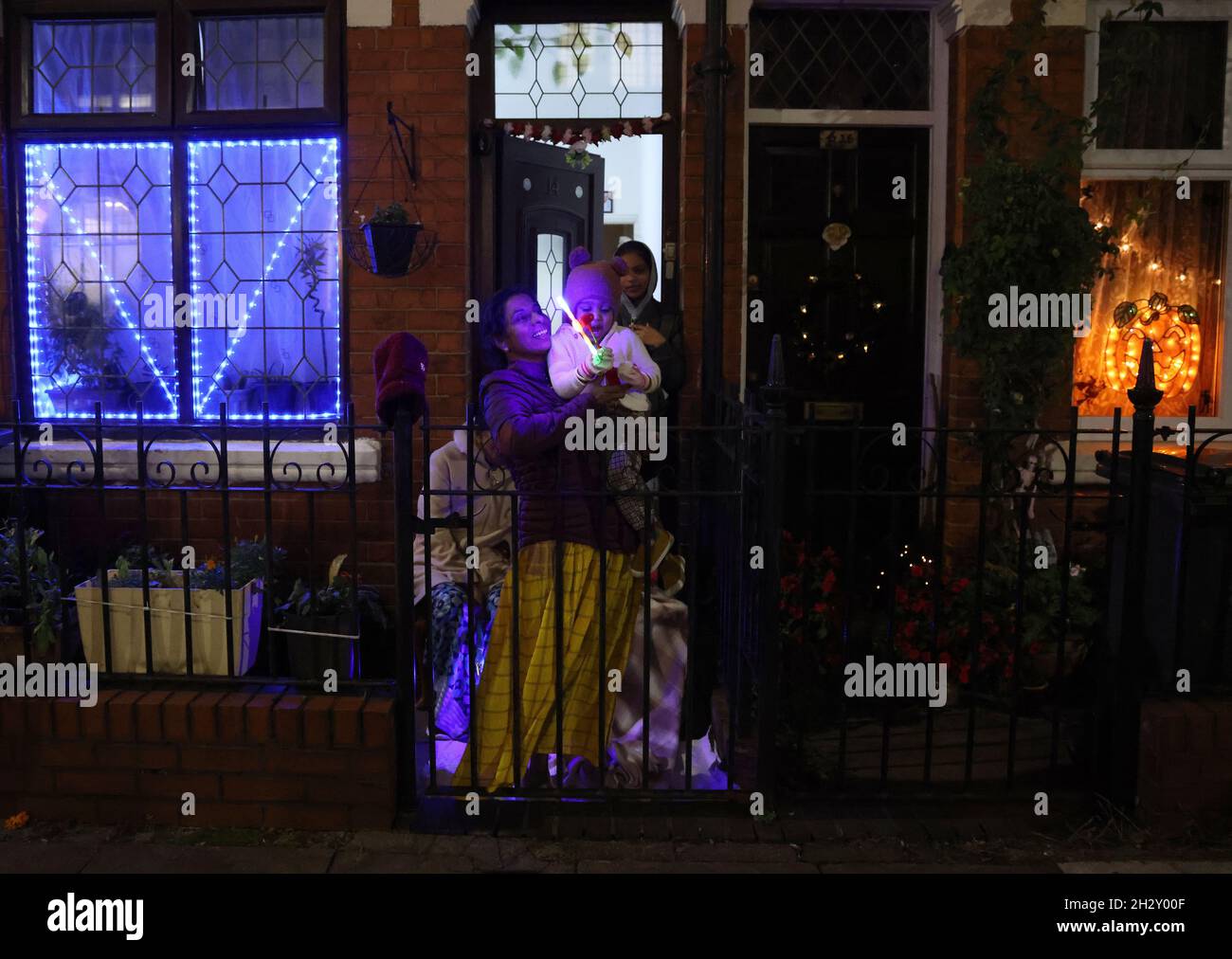 Leicester, Leicestershire, UK. 24th October 2021. A family stand in their garden after the Diwali lights switch on event which was different from normal with no main stage or firework display because of Covid-19 worries. Credit Darren Staples/Alamy Live News. Stock Photo