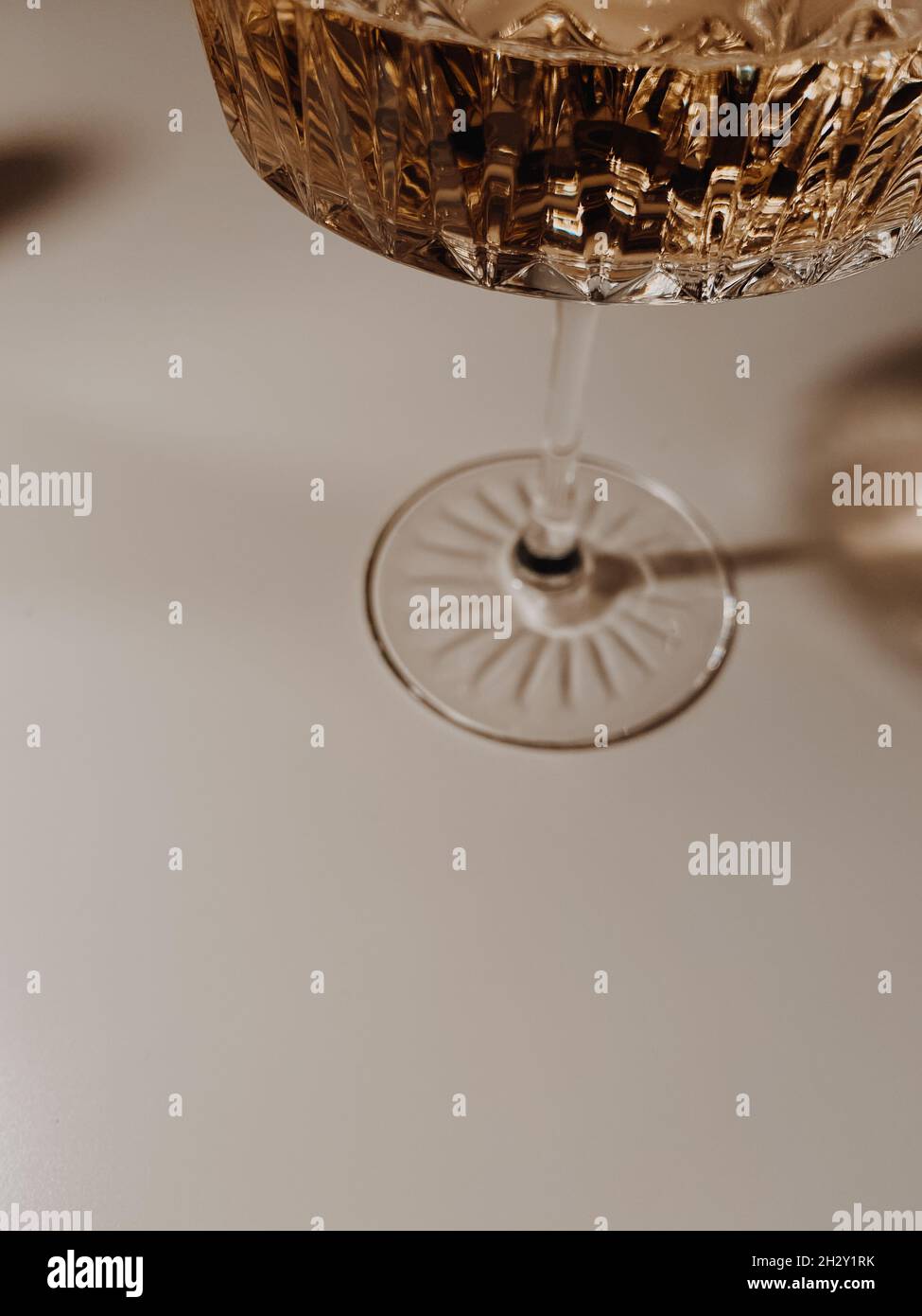 Close-up of a crystal glass with champagne, which flashes on a white wooden table background Stock Photo