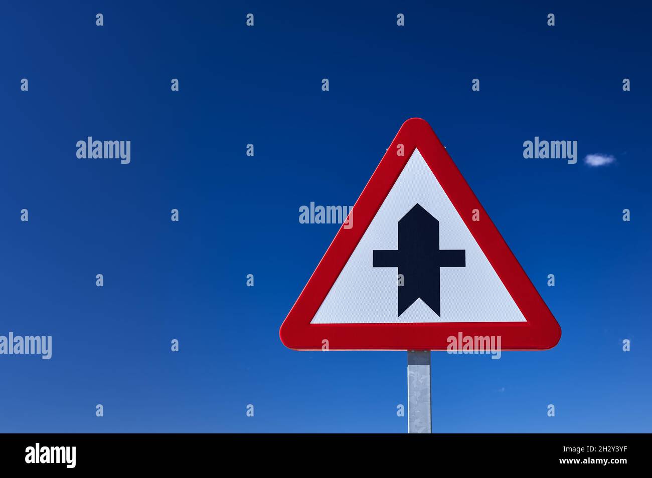 detail of a crossroad ahead traffic sign in blue sky Stock Photo