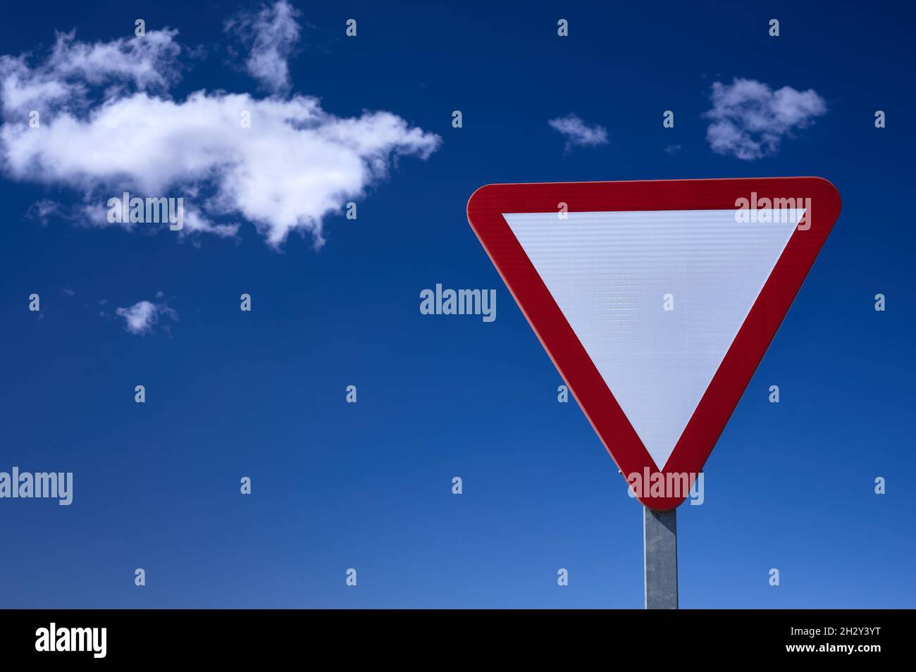 detail of a give way traffic sign over a blue and cloudy sky Stock Photo