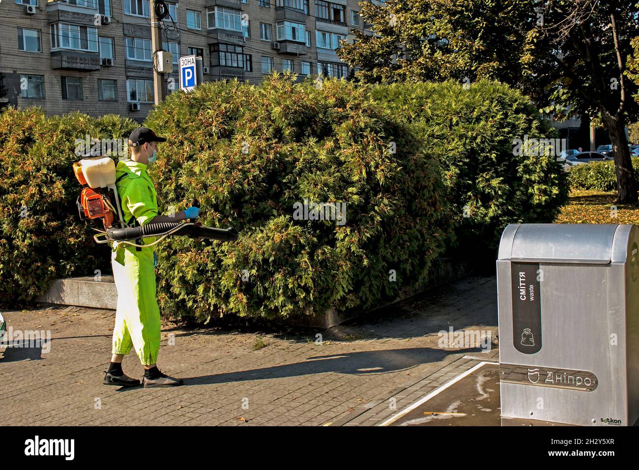 Dnepropetrovsk, Ukraine - 10.05.2021: An employee of the city municipal service sprays plants of the urban landscape. Stock Photo