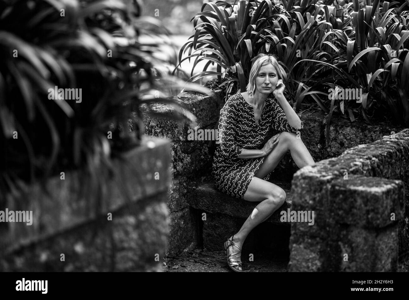 A woman sits on a stone bench in an old park, Porto, Portugal. Black and white photo. Stock Photo