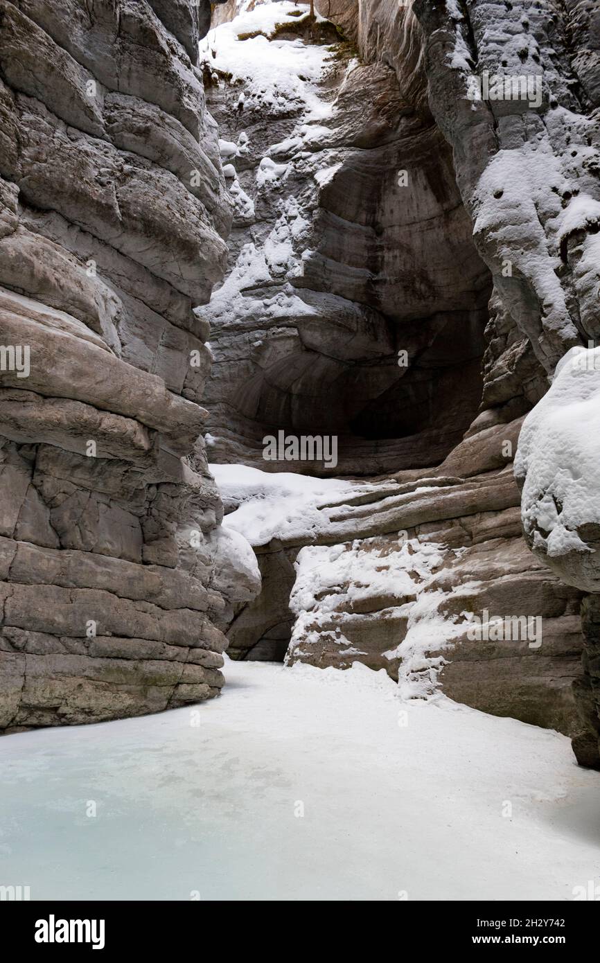 Walking through the bottom of the deepest park of Maligne Canyon during a winter ice-walk, there is a cave in the wall ahead Stock Photo