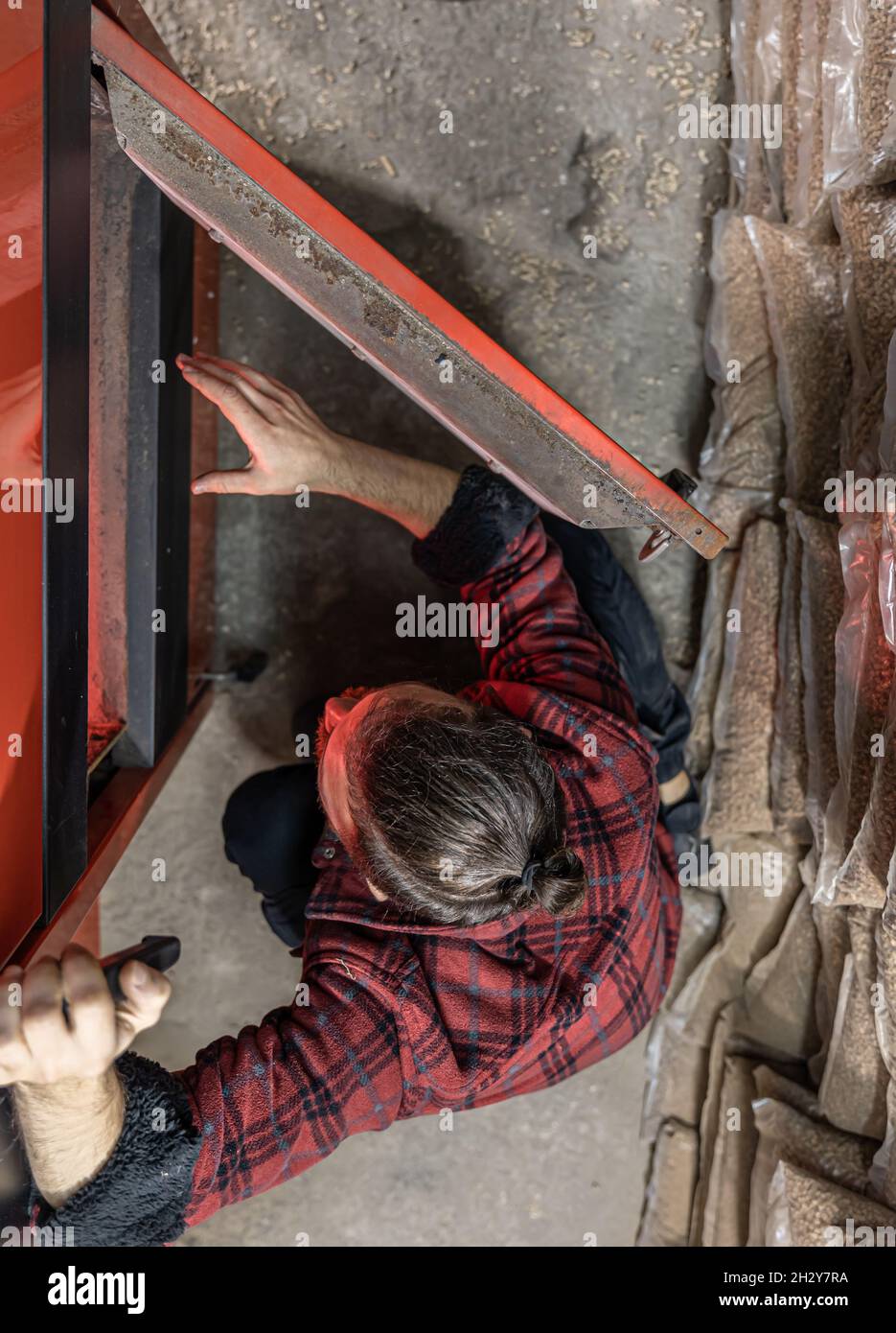 A man looking into a boiler on solid fuel, open door boiler with flames of fire Stock Photo Alamy
