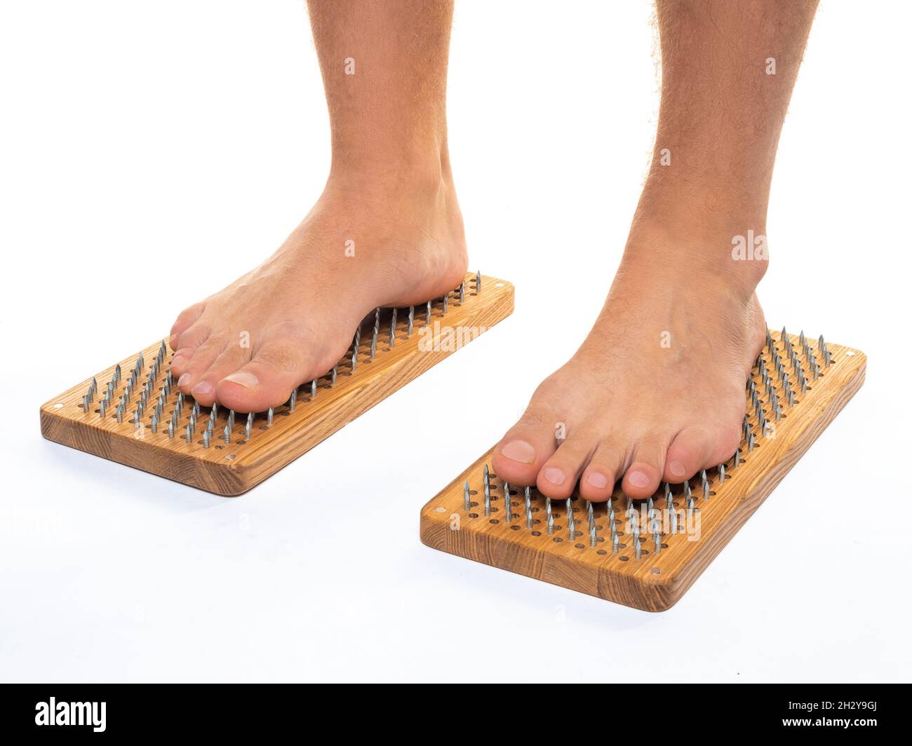 Photo of a male feet stand on a board with sharp nails over white