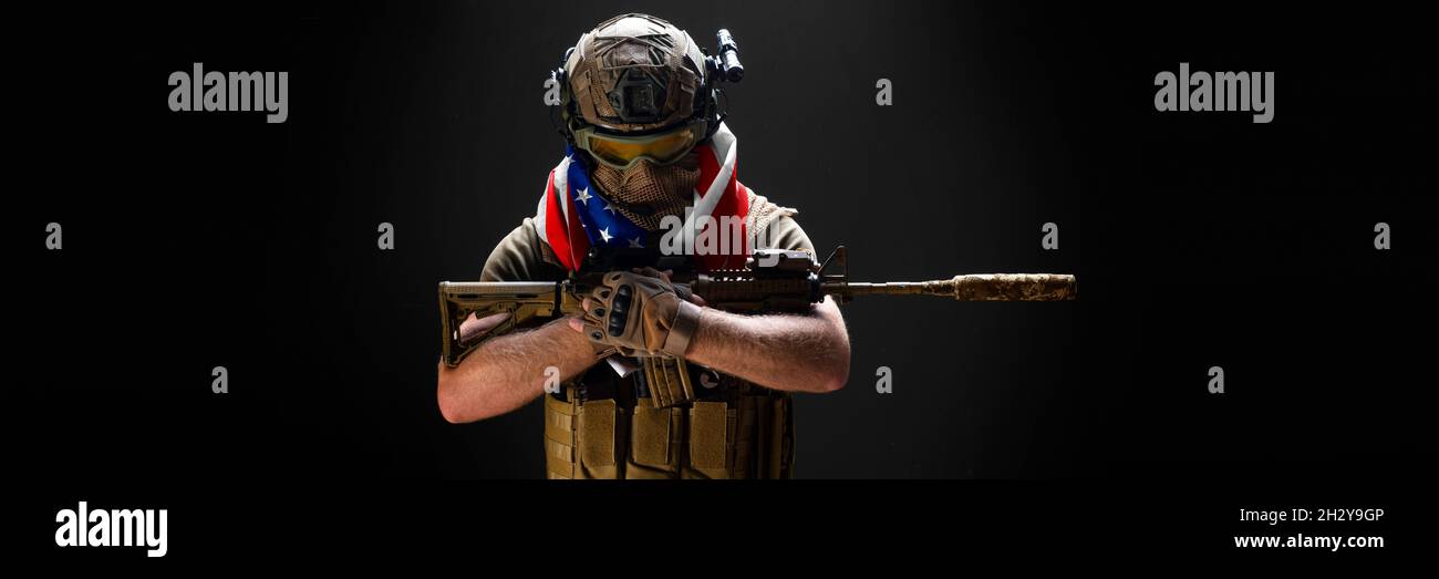 An American soldier stands against the background of a concrete wall ...