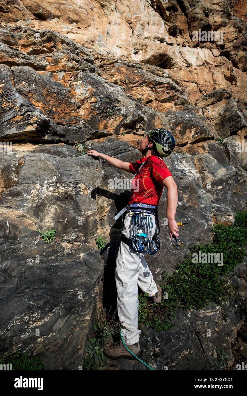 Female rock climber with clim and placing rock climbing safety gear in