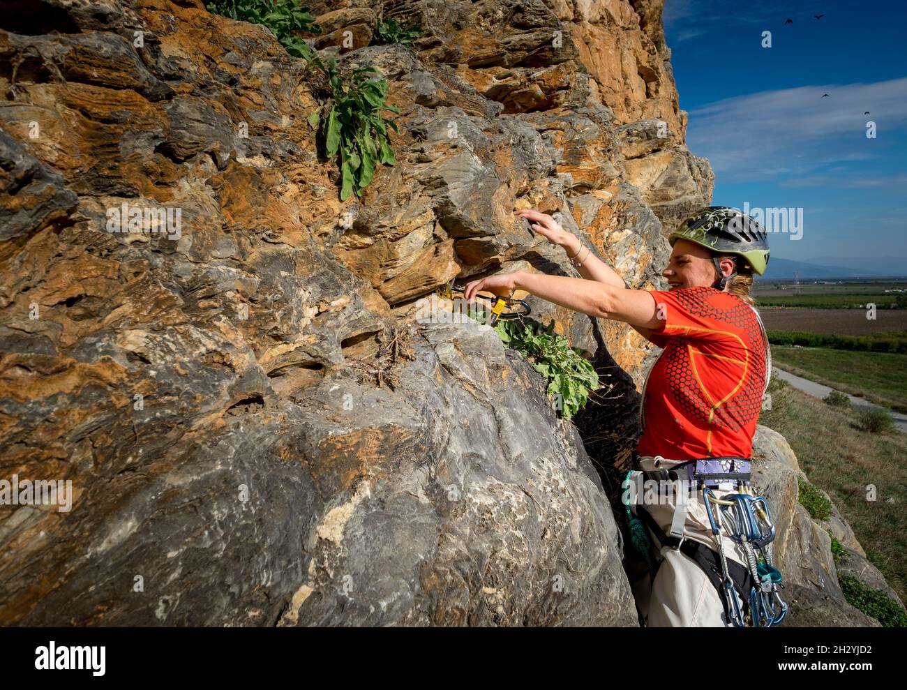 Female rock climber with clim and placing rock climbing safety gear in the rock Stock Photo