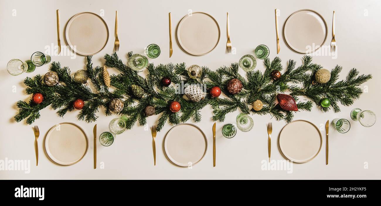 Flat-lay of Christmas table setting with white dinnerware and branches Stock Photo