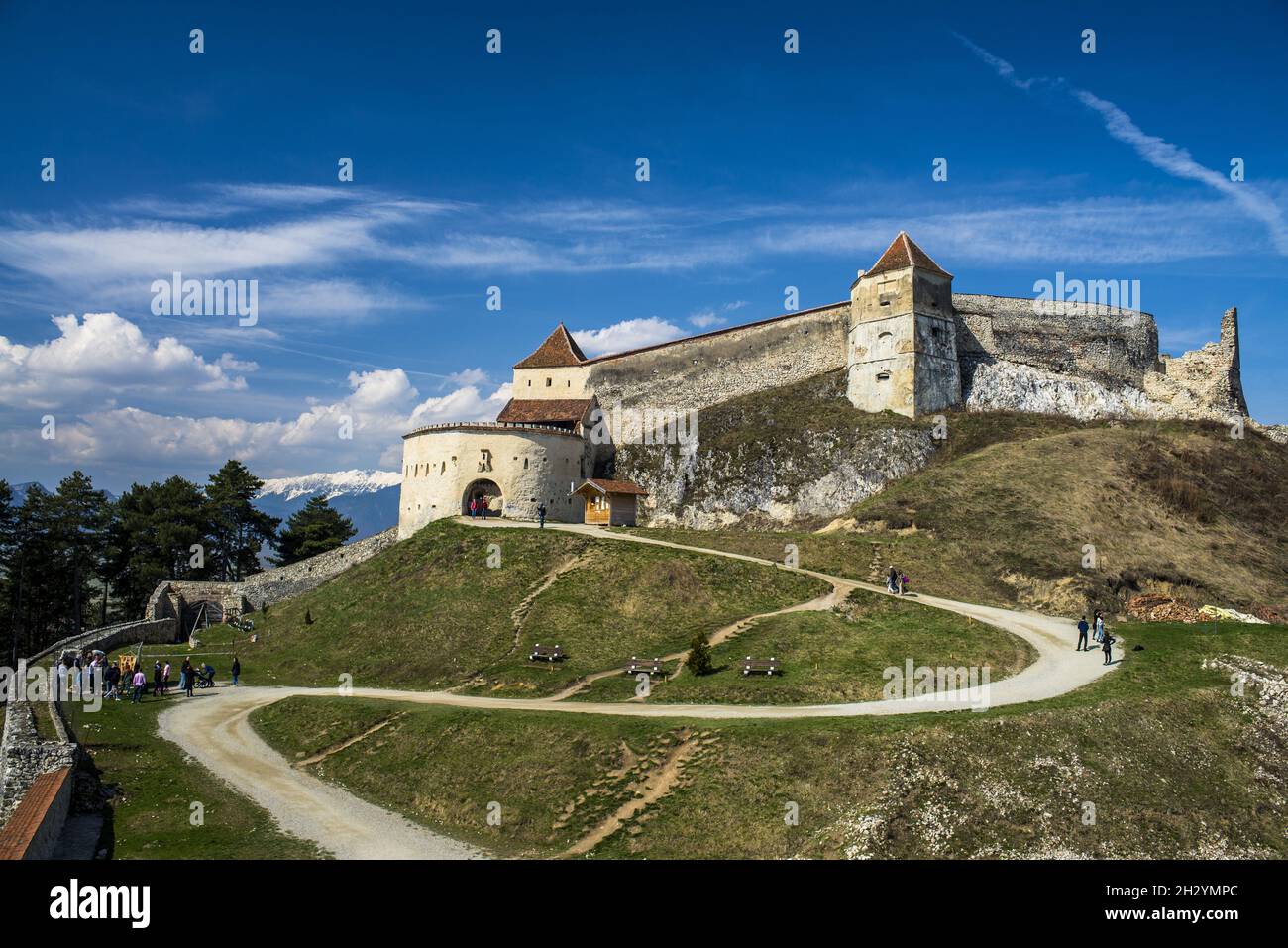 The Rasnov Fortress on a hill under a blue sky and sunlight in Romania ...