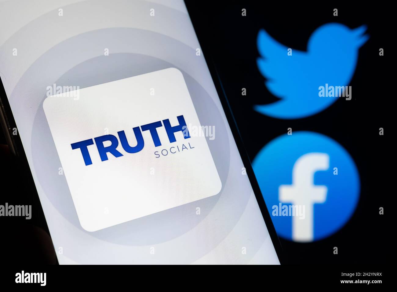 Truth Social app logo seen on the smartphone with blurred Facebook and