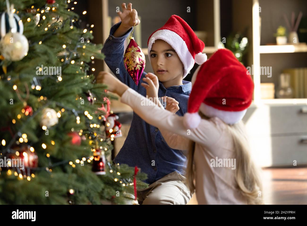 Happy cute little children siblings decorating Christmas tree Stock ...
