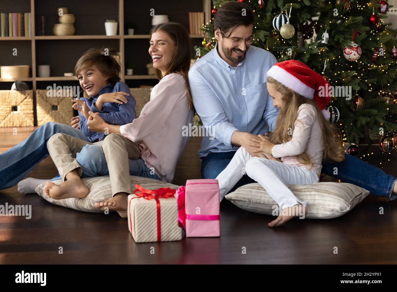 Happy parents having fun with children near Christmas tree. Stock Photo