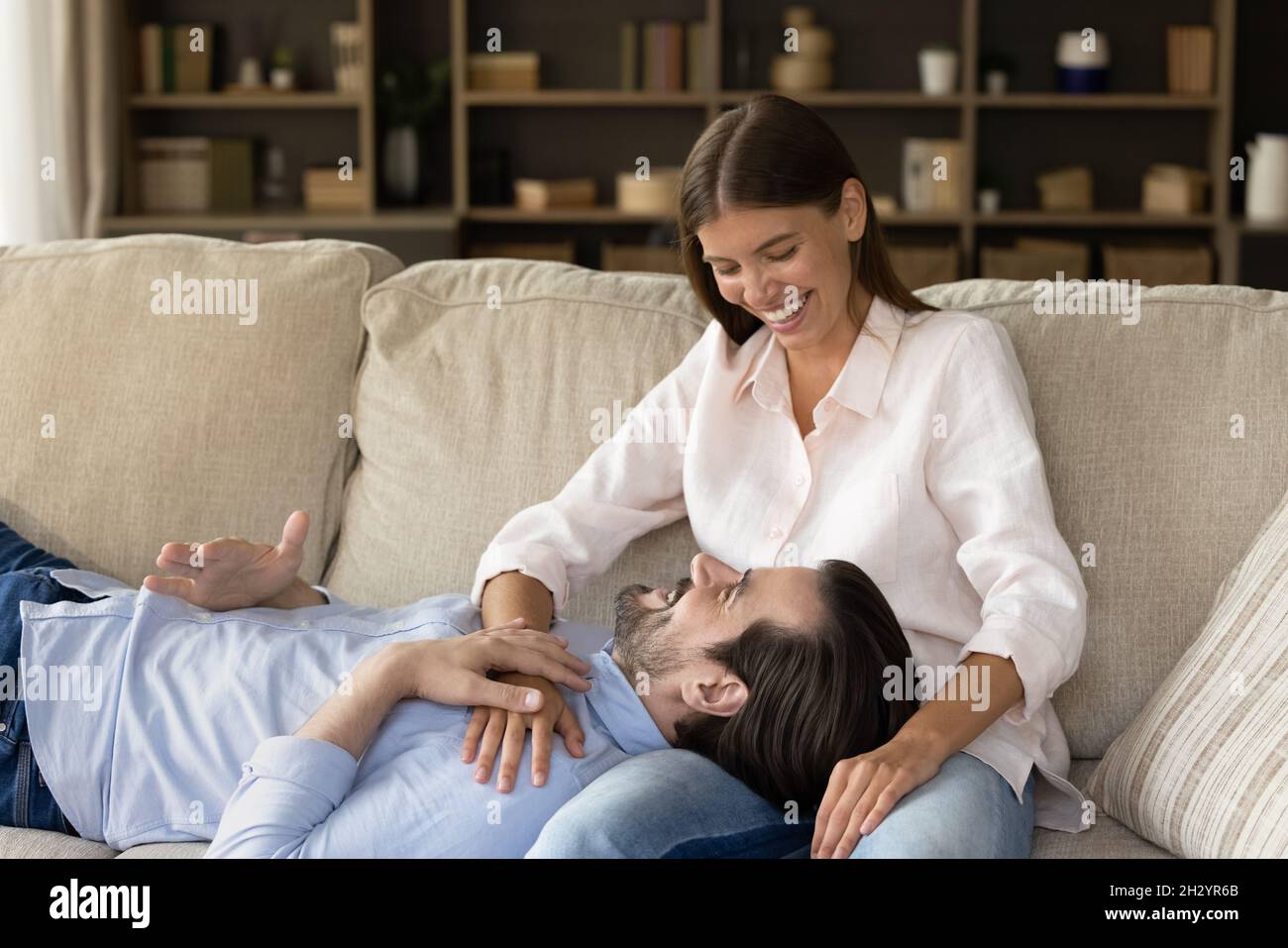 Happy young man resting on sofa with loving woman. Stock Photo