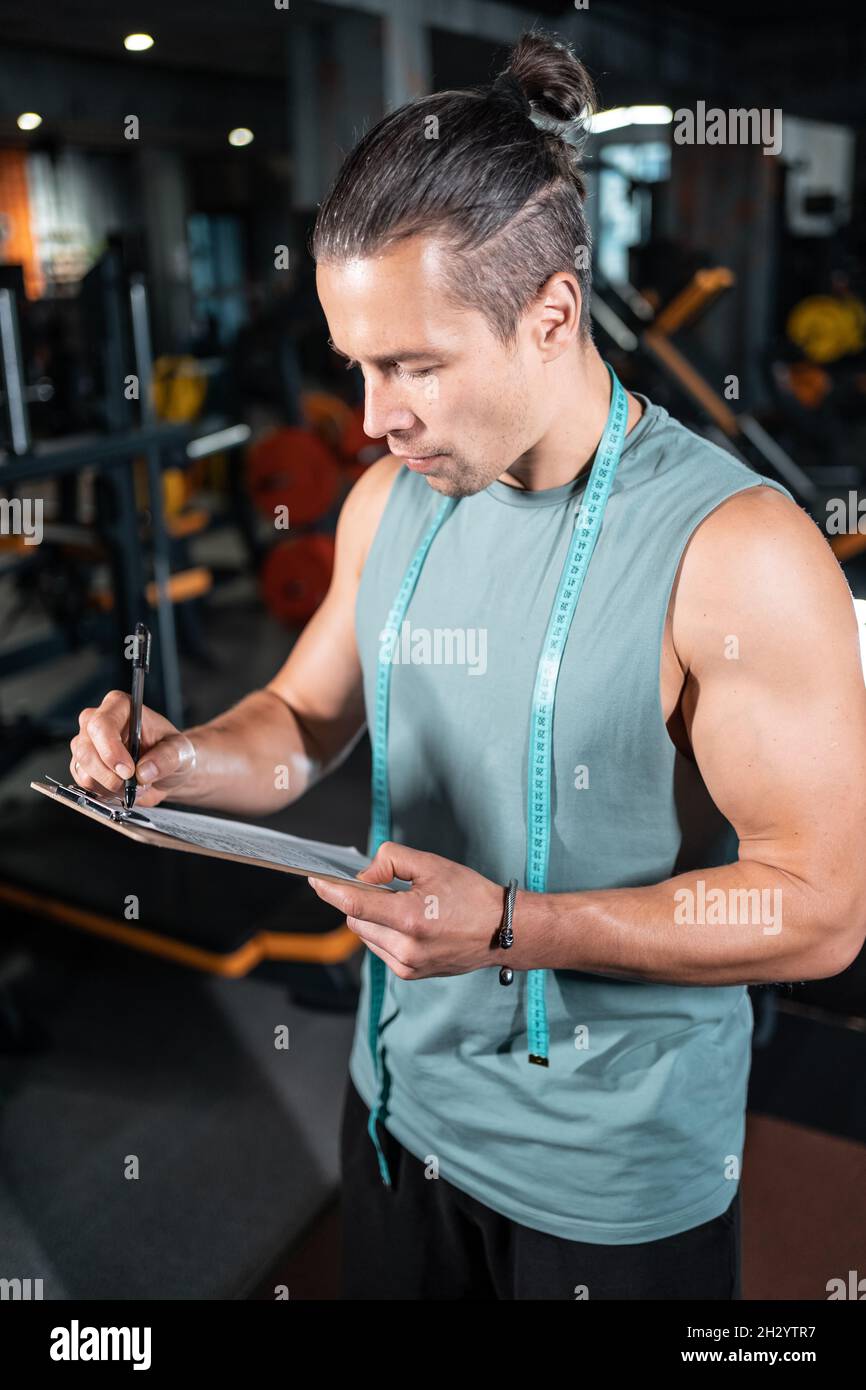 young attractive man personal trainer planning workout with clipboard