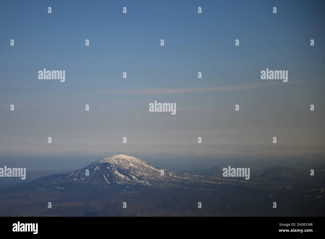 Hekla volcano, Iceland, snow-capped mountain beneath a dusky blue sky with white clouds. Stock Photo