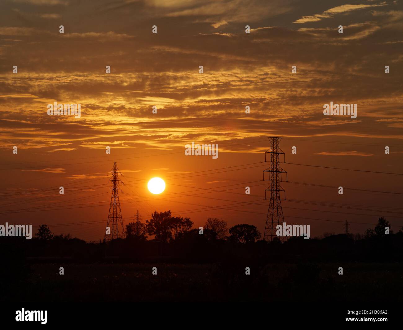 The sun setting behind electrical power lines. Quebec,Canada Stock Photo