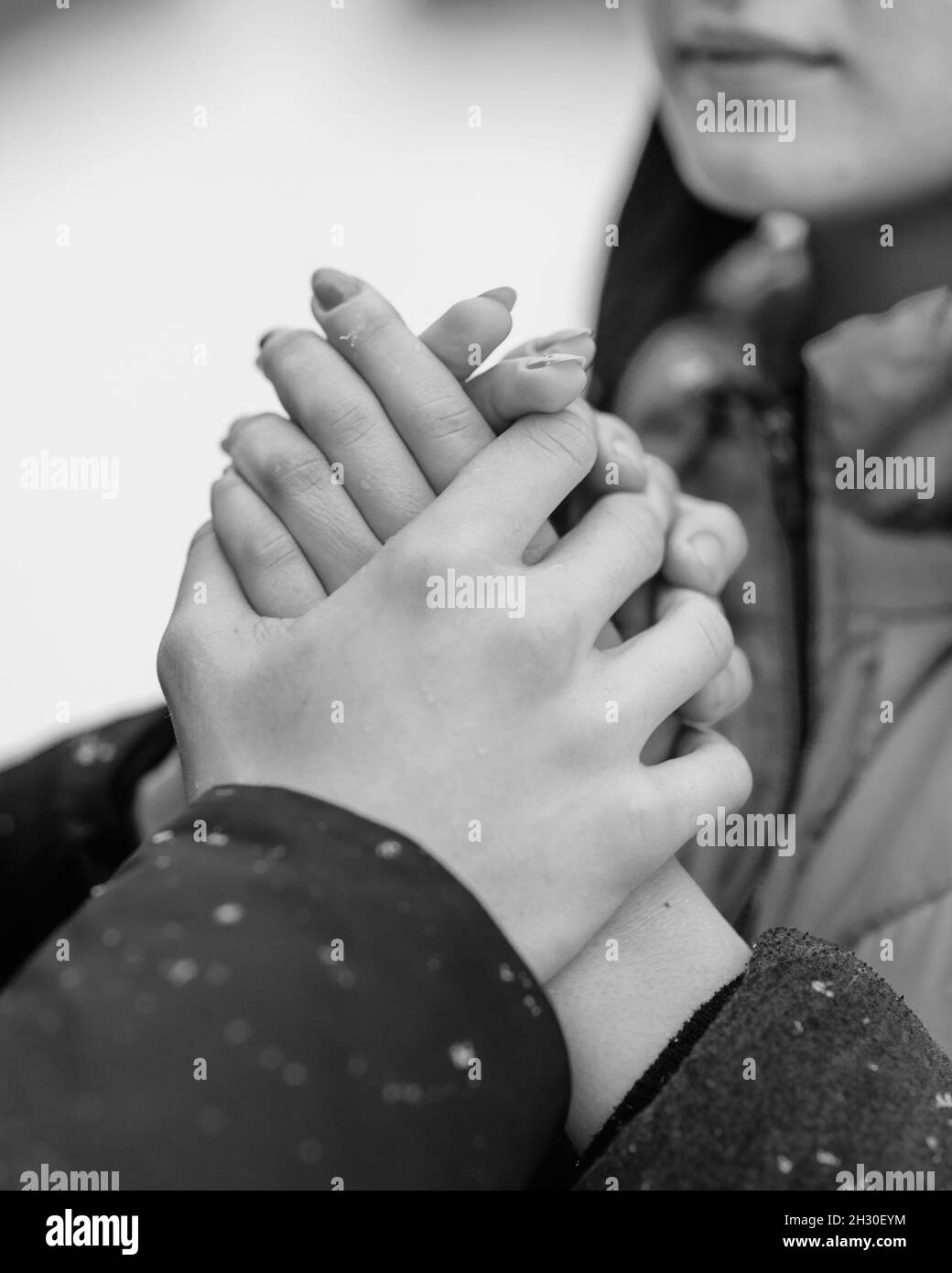 Couple of teenagers walking in winter forest. Boyfriend warming girlfriend's hands. Black and white Stock Photo