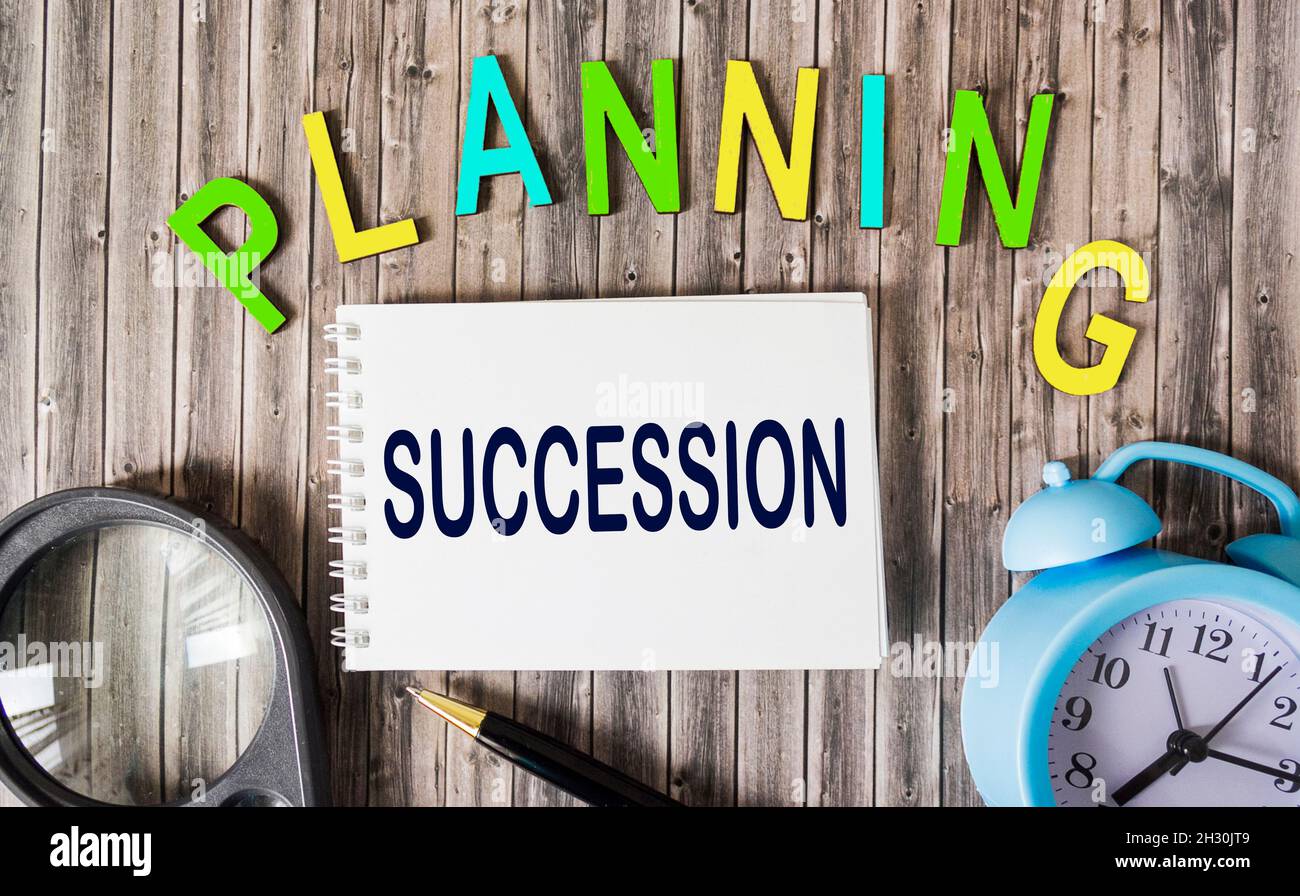 Successions Clock Succession planning concept on notepad and wooden letters on wooden ...