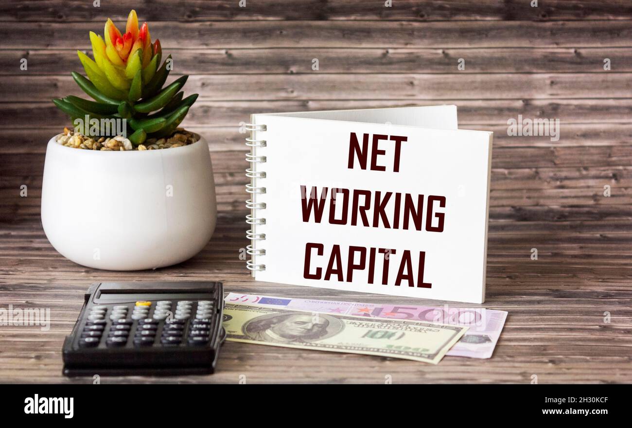 Net working capital, text on notepad with calculator and money on wooden table with cactus. Stock Photo