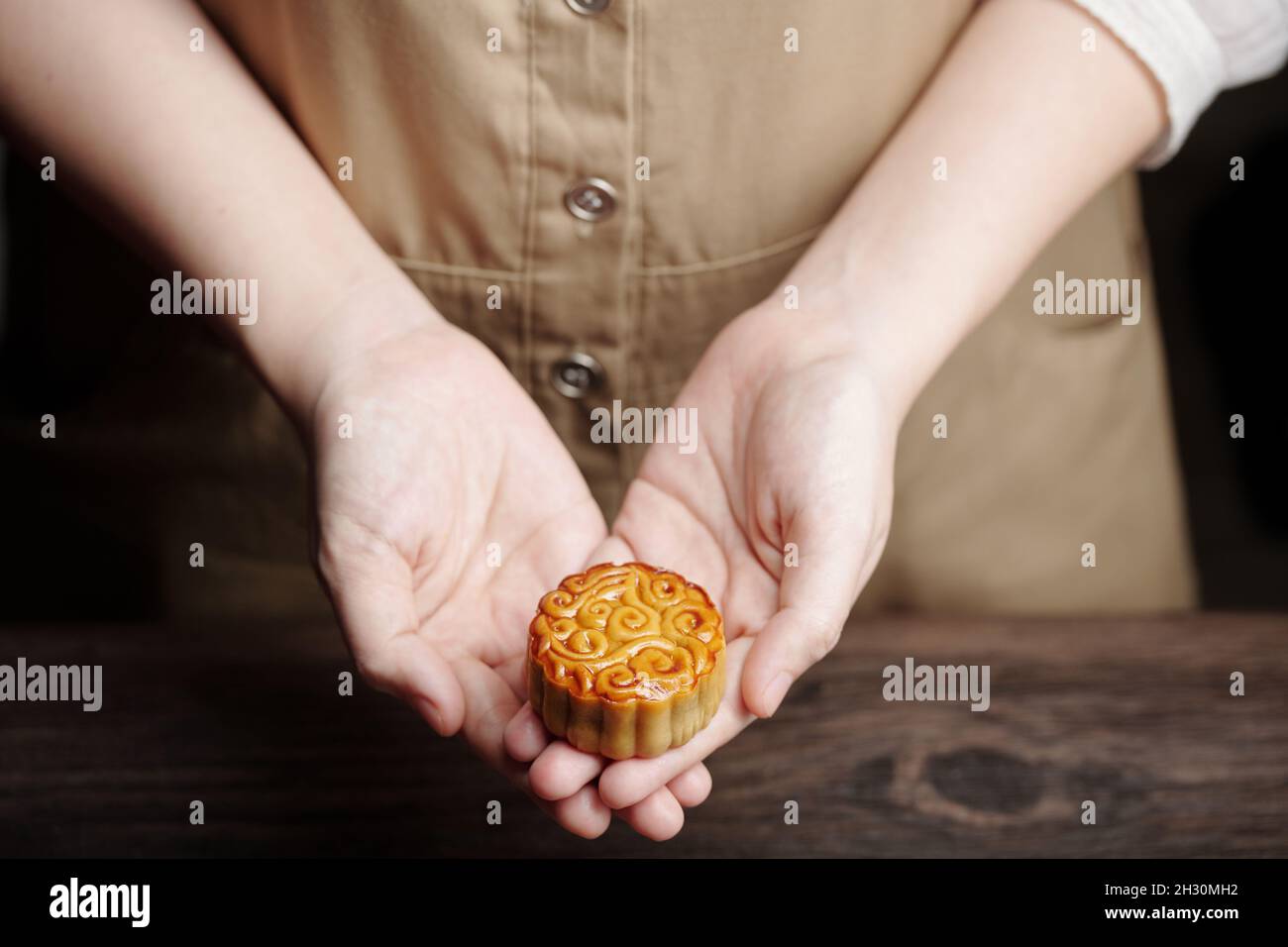 Close-up image of young woman giving small mooncake glazed with eggwash ...