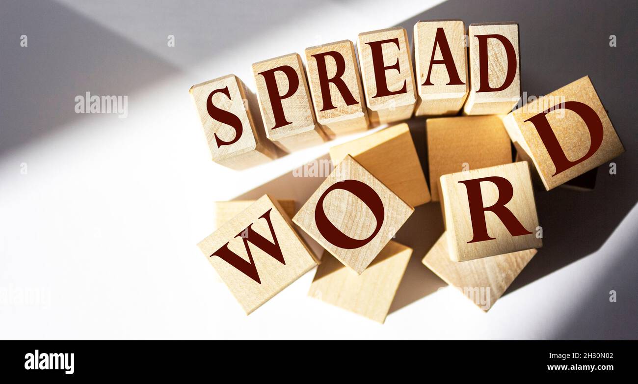 Spread the word written on a wooden block. Spread word text on white table, concept. Stock Photo