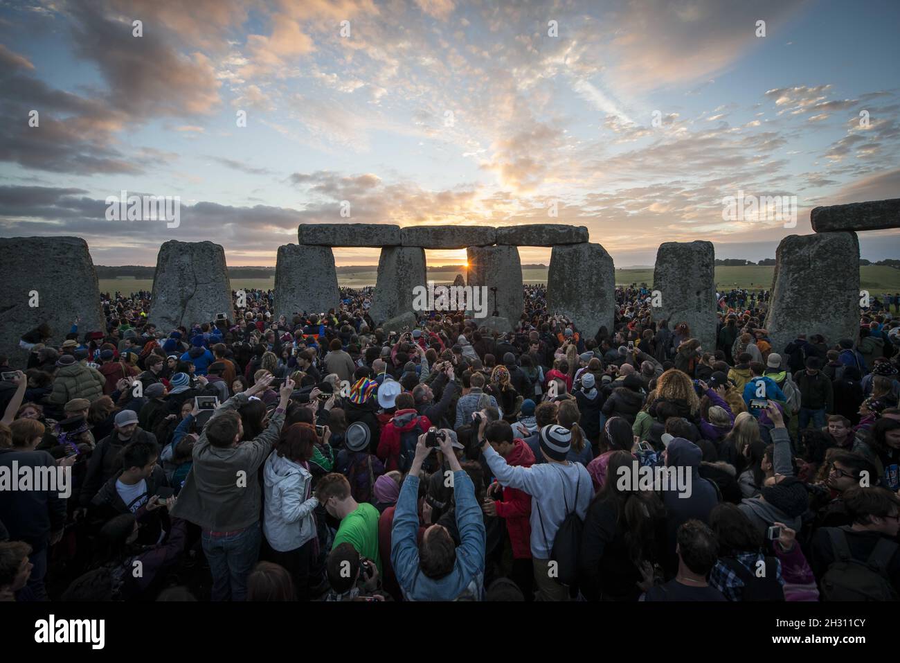 General view of the sun rising and shining through the stones at Stonehenge on the morning of the Summer Solstice at Stonehenge - Salisbury Stock Photo