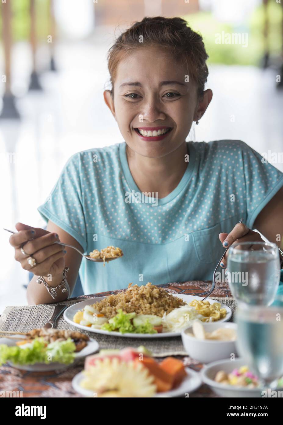 Indonesian woman enjoys a Rendang Curry prepared in a restaurant in